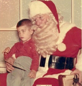 A three-year-old on Santa’s lap in a Virginia Department store, circa 1961. The child appears to be a bit fearful as to his status regarding The Naughty and Nice List. 